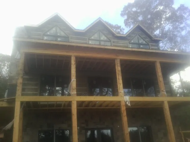 Dormers and porch framing on a large log home under construction — Roof Coating work by our crew in Parsonsfield