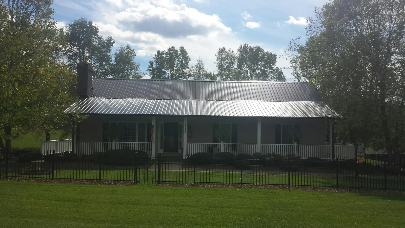 Gray metal roof on a brick ranch with a full width front porch — Gutter Guard Installation work by our crew in Parsonsfield