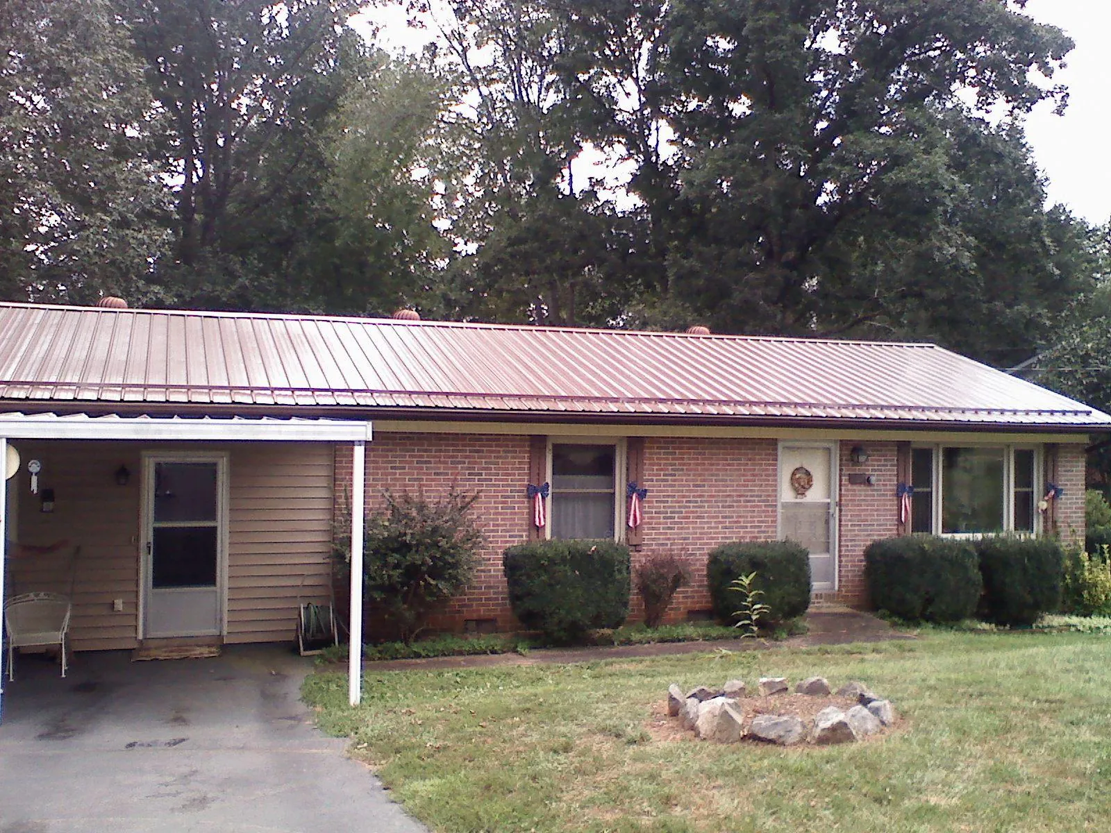 Bronze metal roof and carport on a brick ranch home — Roof Repair work by our crew in Parsonsfield