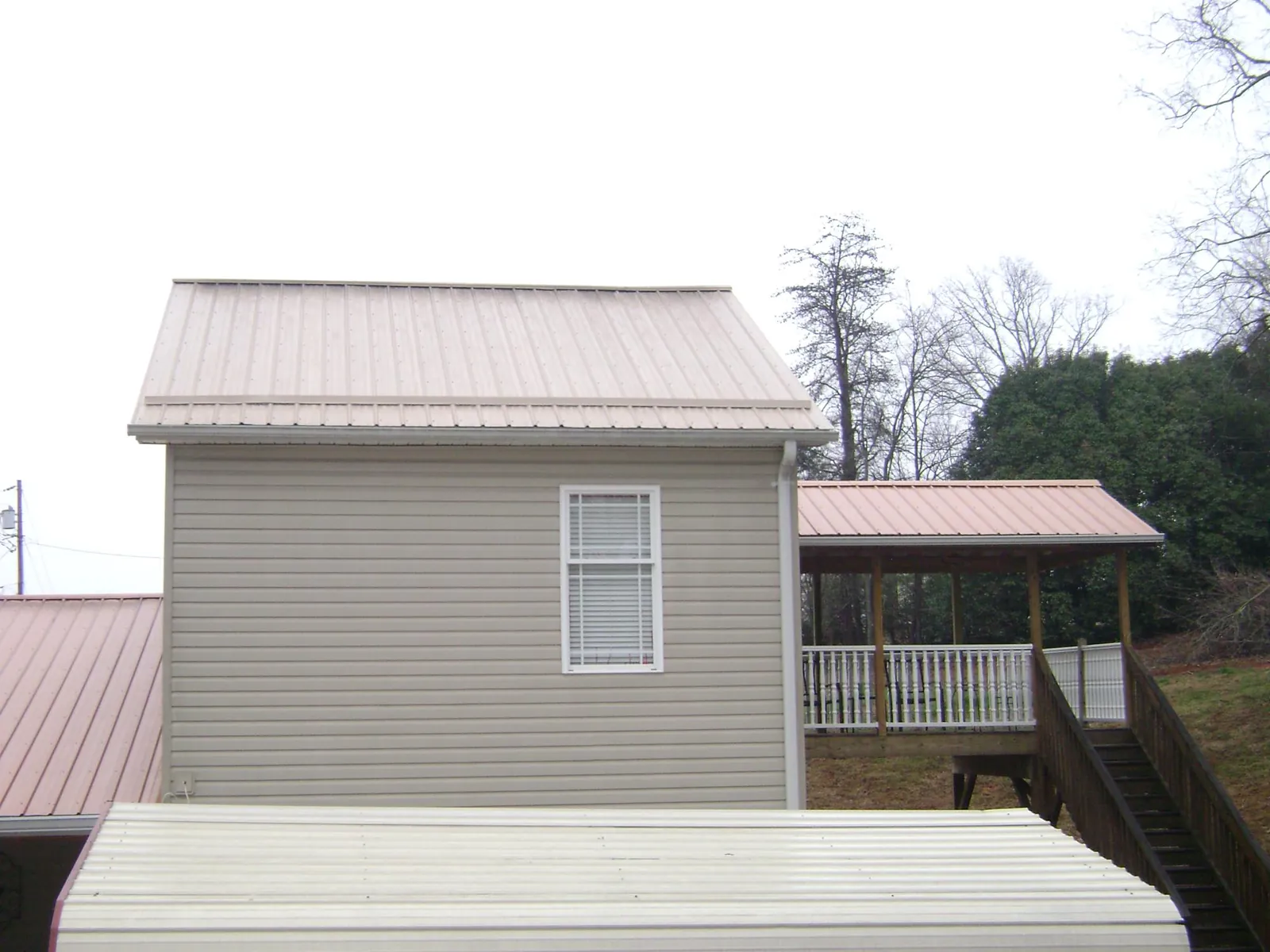 Tan metal roofs on a two story addition and attached porch, from a Roof Replacement job in Parsonsfield