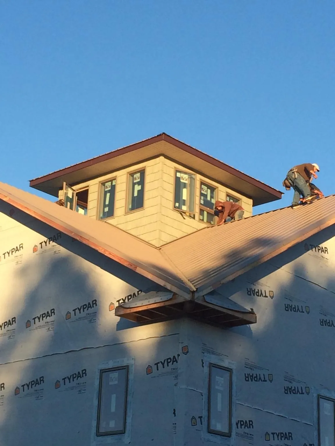 Roofers working around a rooftop cupola on a new metal roof at sunset — Roof Waterproofing in Parsonsfield by Roofing Brothers